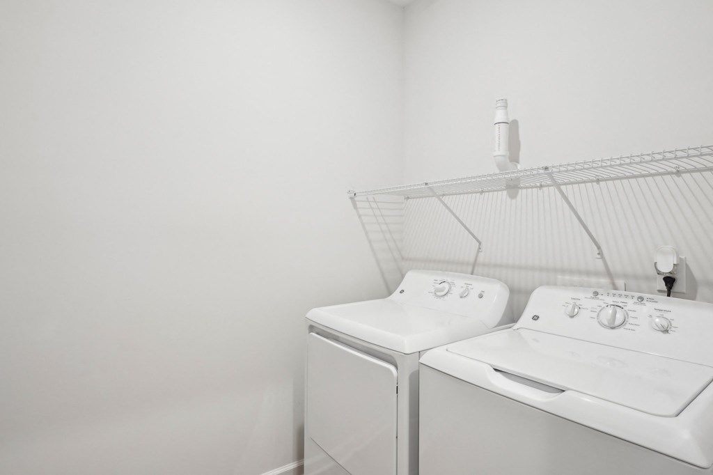 Two white washing machines in a laundry room.