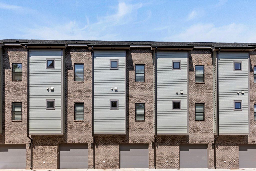 A row of identical houses with grey siding and brick pillars.
