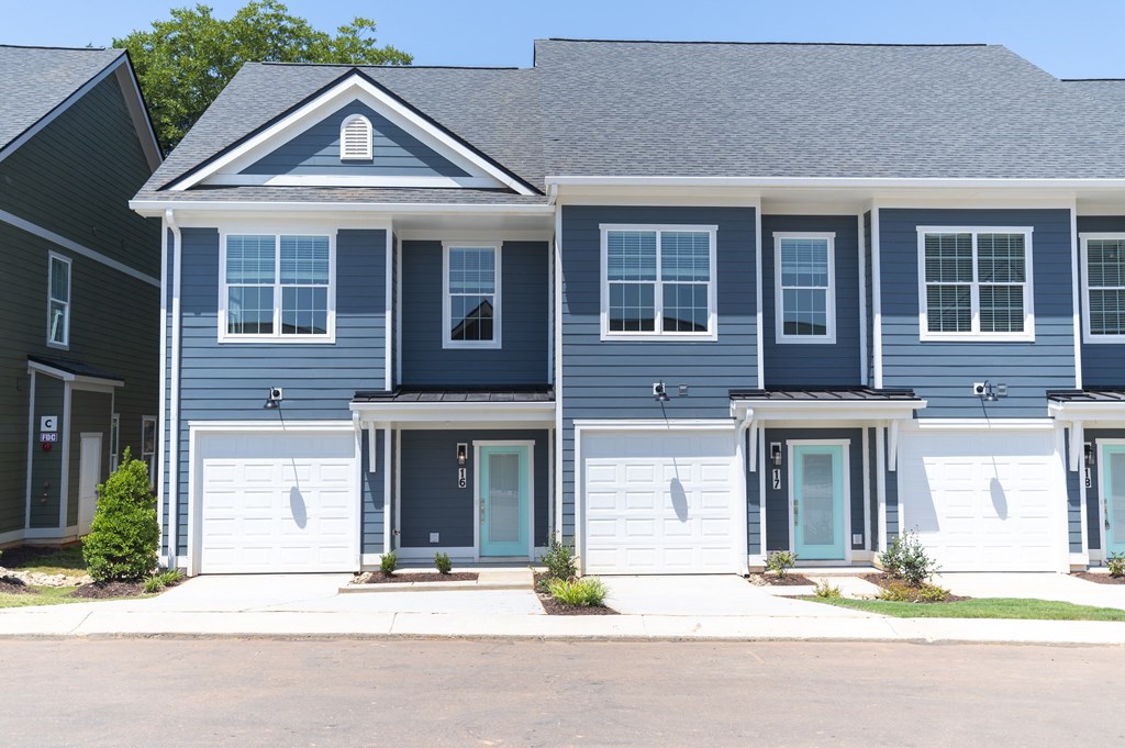 a blue house with white garage doors at Landon Green Artisan Cottages Apartments, Hickory, NC, 28601