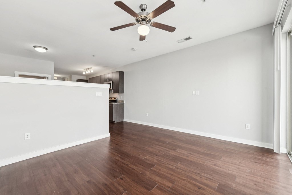 A room with a ceiling fan and wooden flooring.