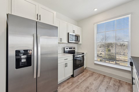 A kitchen with a stainless steel refrigerator and a microwave above the stove.