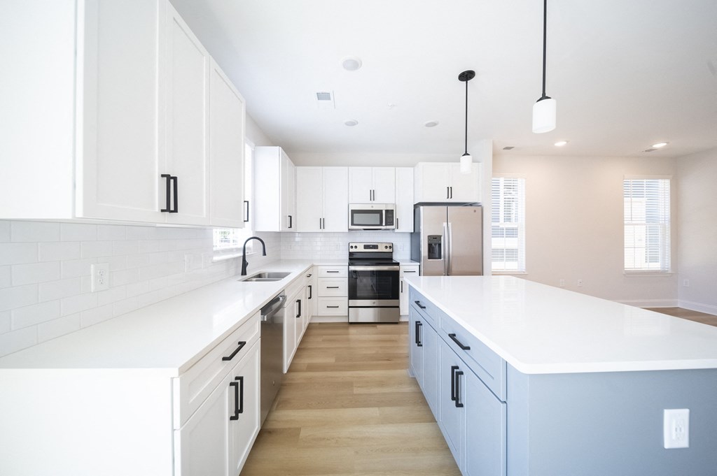 a kitchen with white cabinets and a large white island at Landon Green Artisan Cottages Apartments, North Carolina