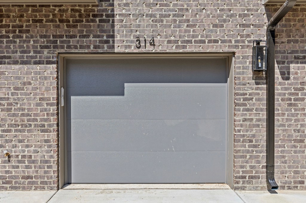 the side of a brick building with a gray garage door at The Collection Charlotte in Charlotte, NC, 28205