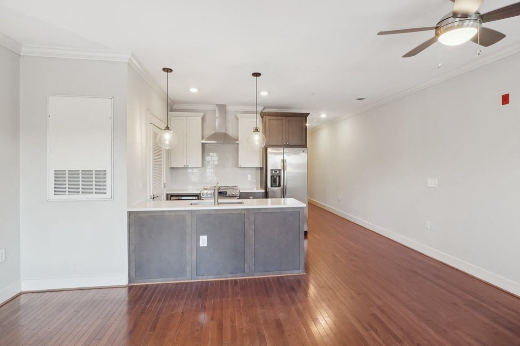 A kitchen with a wooden floor and a ceiling fan.
