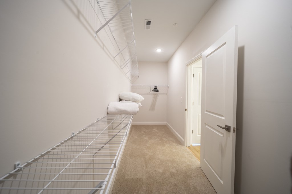a walk in closet in a bedroom with white walls and carpet at Landon Green Artisan Cottages Apartments, North Carolina, 28601