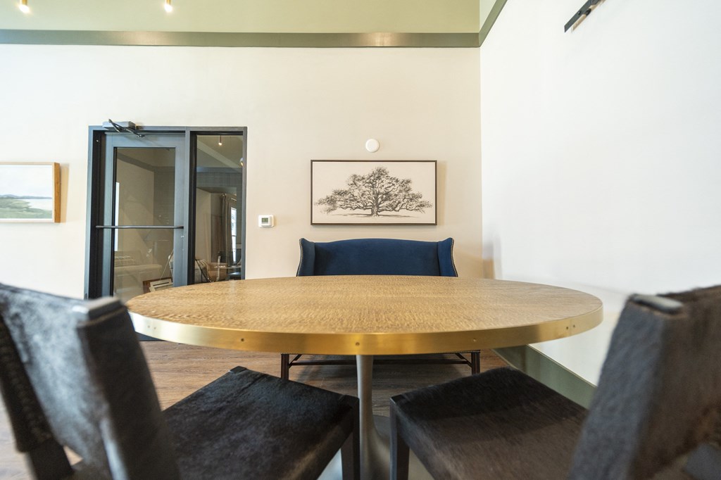 a round wooden table with a blue chair in a room with white walls and a painting on at Landon Green Artisan Cottages Apartments, North Carolina