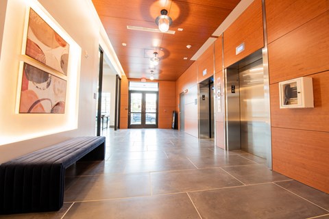 a hallway with a bench and elevators in a building