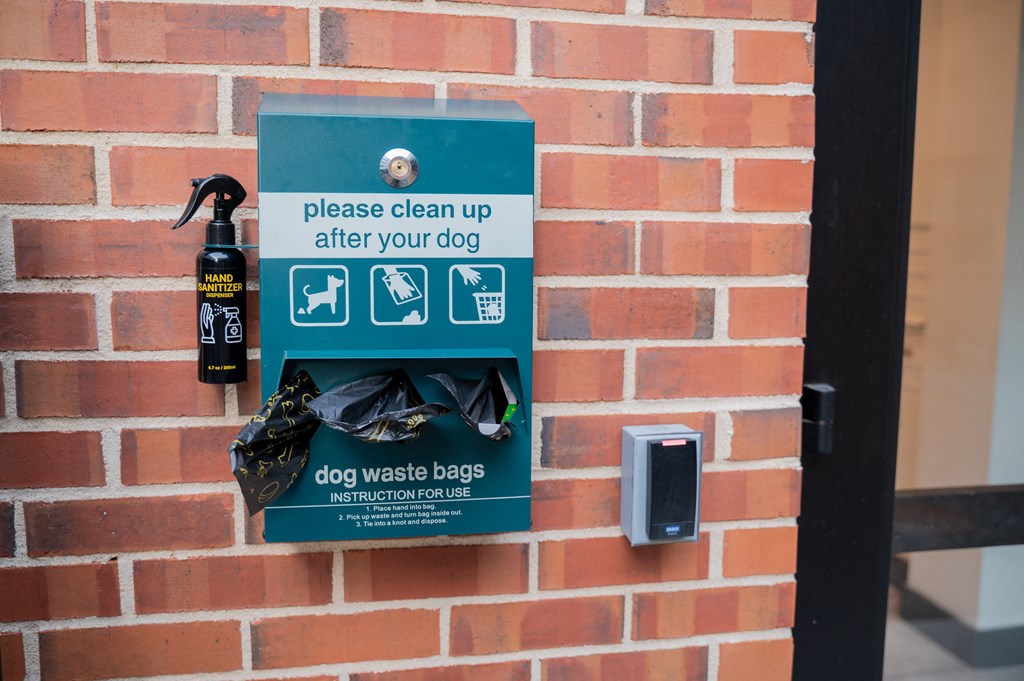 a sign that says please clean up after your dog and a bottle of dog waste