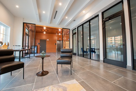 a lobby with chairs and a table in front of glass doors
