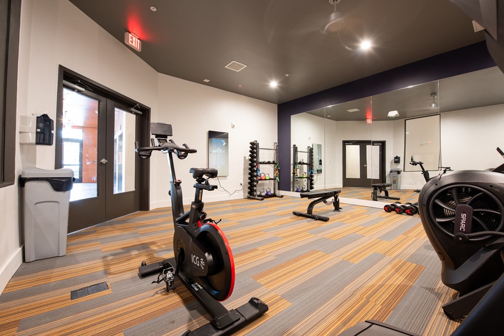 2200 sq ft gym with cardio machines and weights on a wood floor