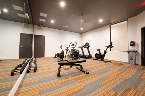 a workout room with treadmills and weights on a wooden floor