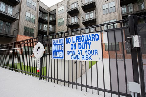 no lifeguard on duty sign on a fence in front of an apartment building