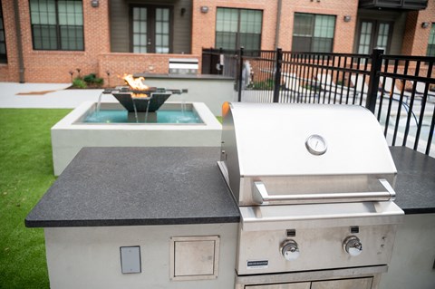 two grills in front of a fire pit in a backyard