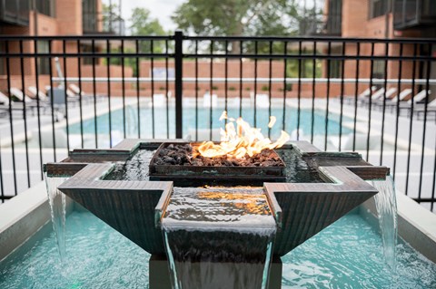 a fire pit in front of a pool with a fence