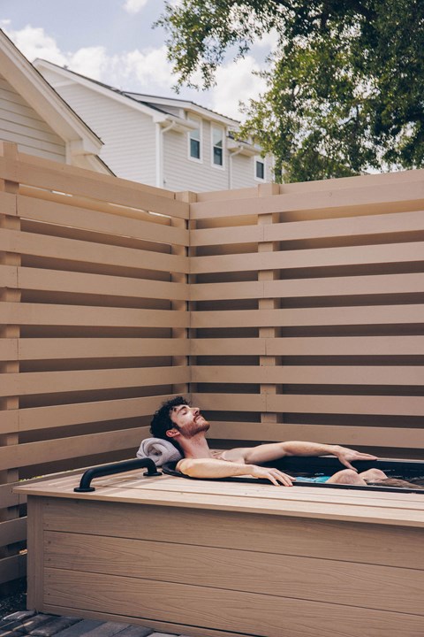 A man is relaxing on a wooden sunbed.