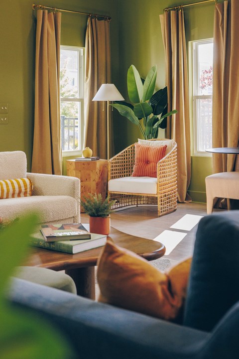 A living room with a sofa, armchair, and a table with a lamp and a plant.