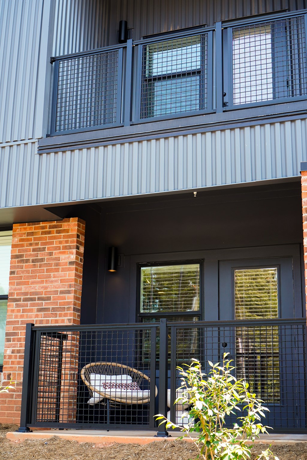 A blue house with a black gate and a brick pillar.