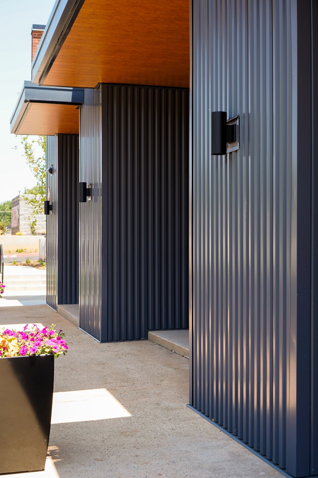 A modern building with dark grey vertical lines and a wooden overhang.
