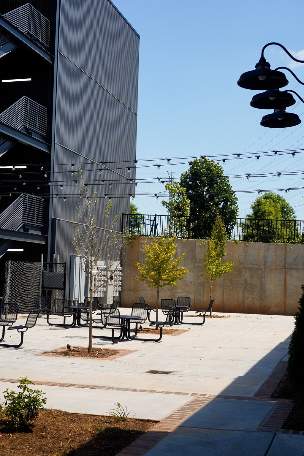 A modern outdoor seating area with benches and a tree in front of a building.
