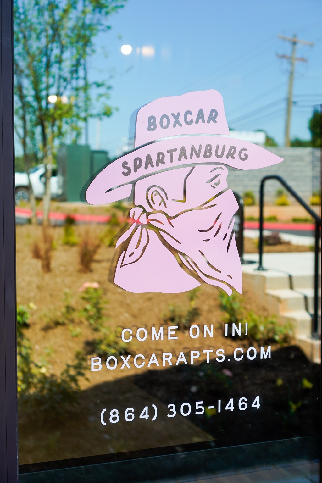 A window display with a pink hat and the words "Boxcar Spartanburg" on it.