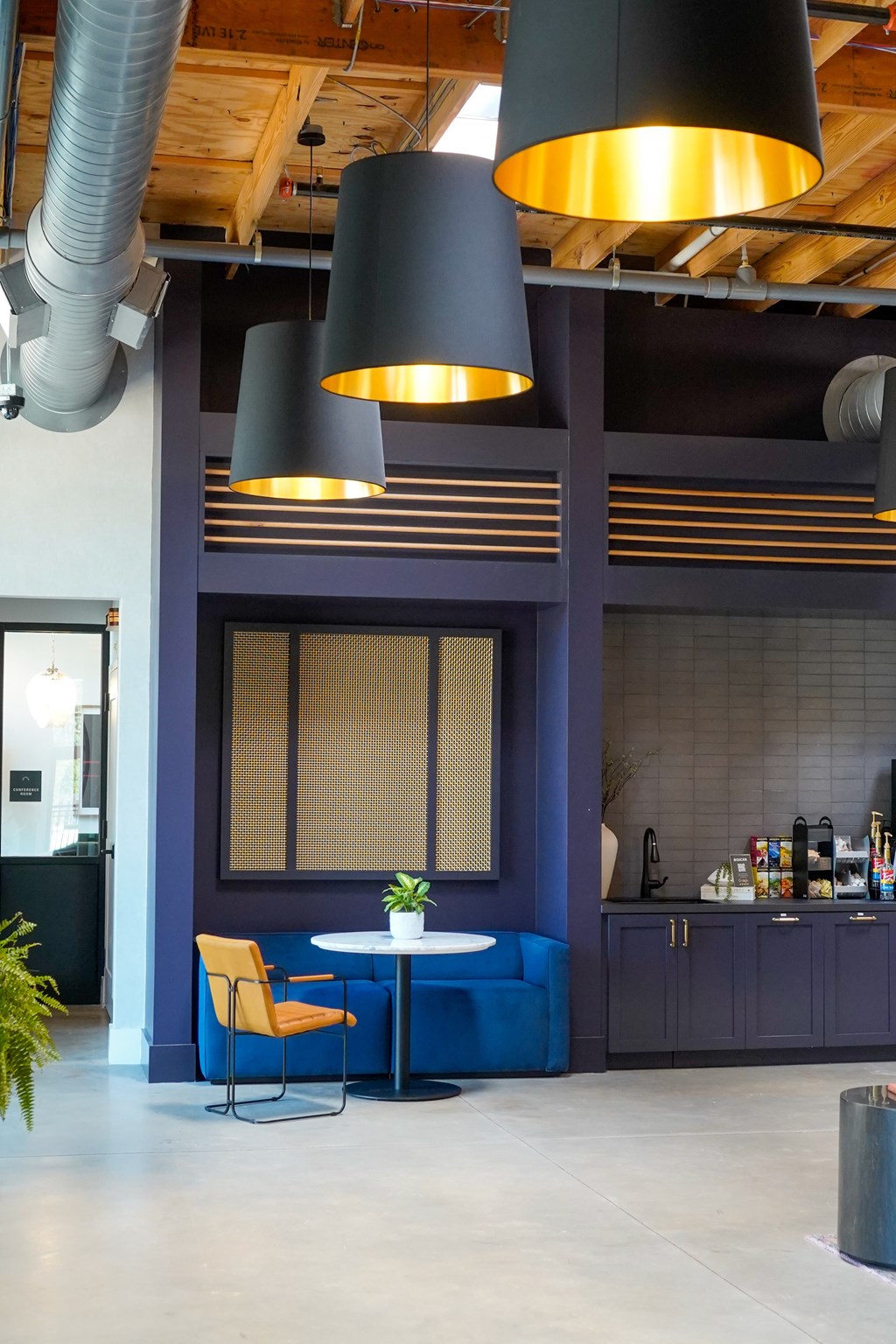 A modern kitchen with a blue island and a yellow chair.