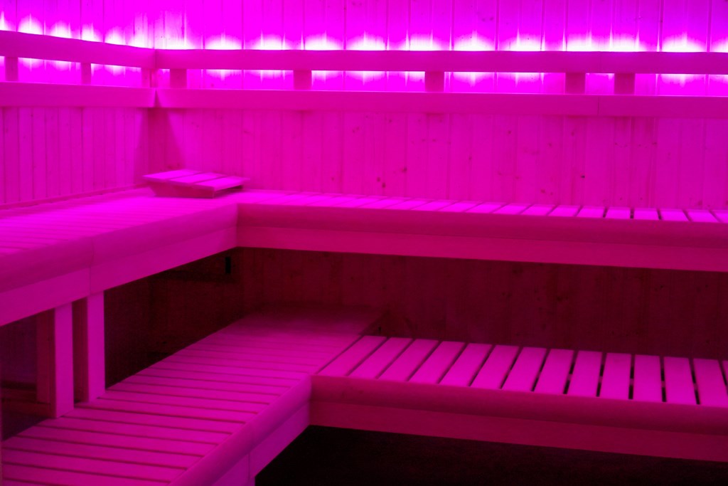A pink lit room with a bench.