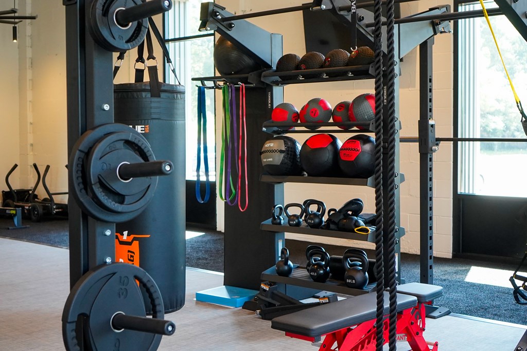 A gym with a weight rack, kettlebells, and a bench.