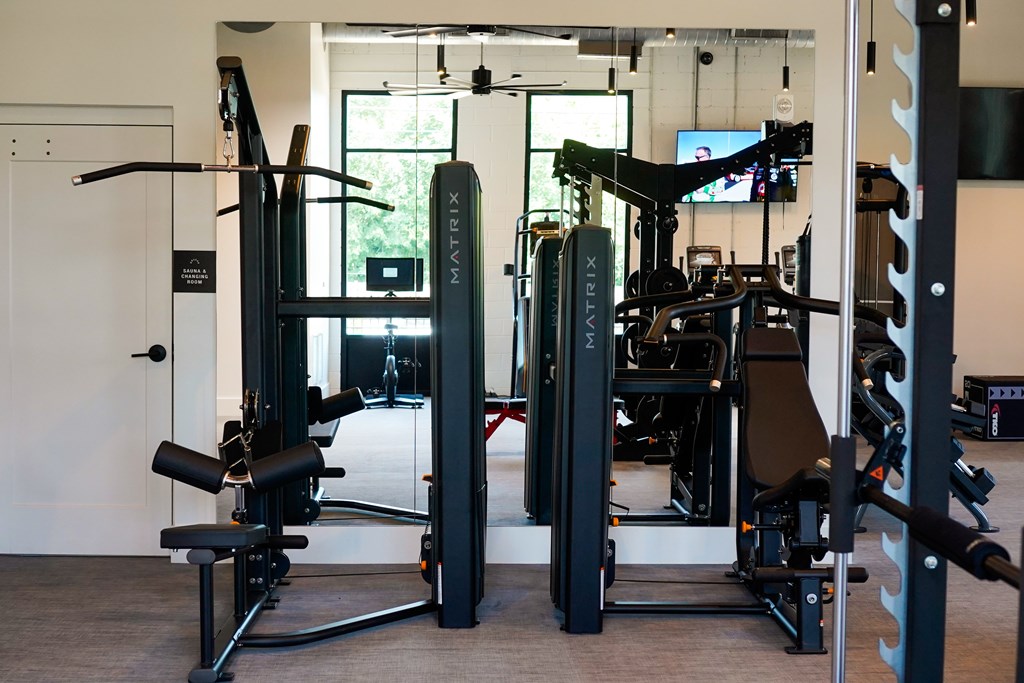 A gym with a variety of equipment including a squat rack and a bench press.