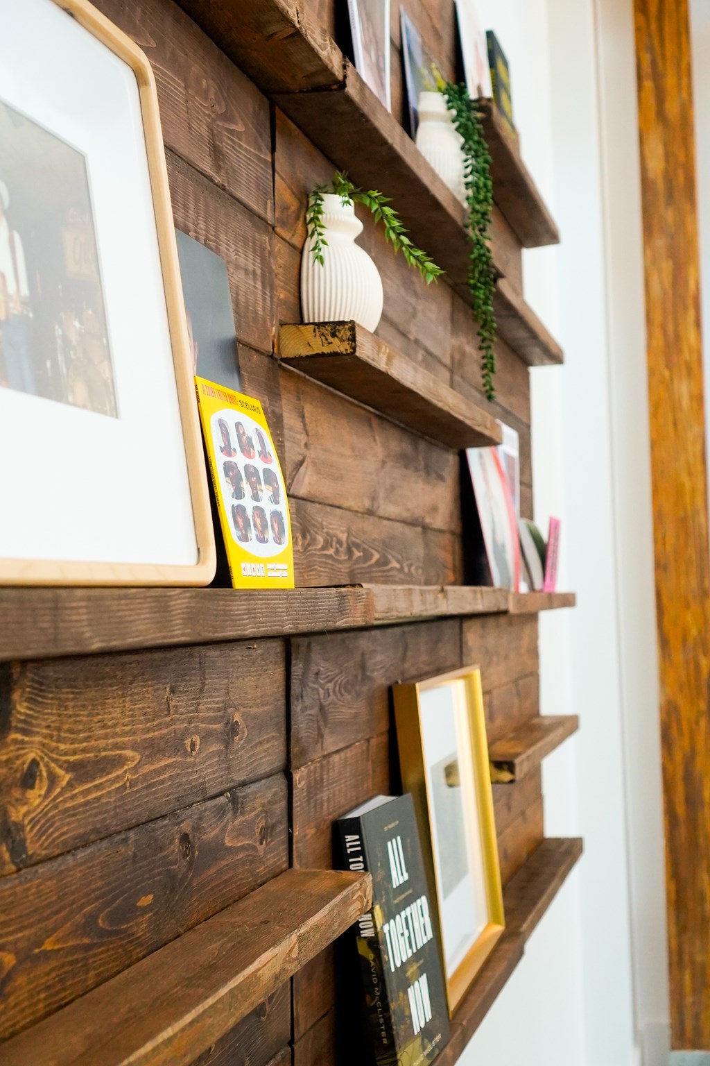 A wooden shelf with a calendar, a potted plant, and a framed picture.