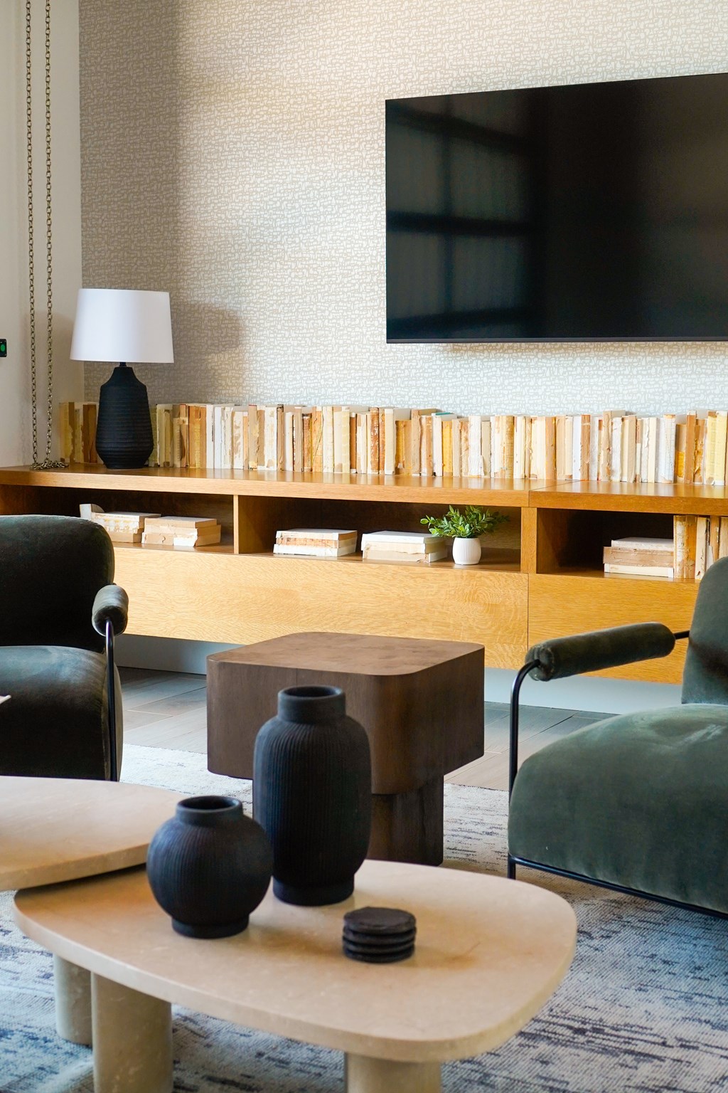 A living room with a green chair, a black vase, and a wooden coffee table.