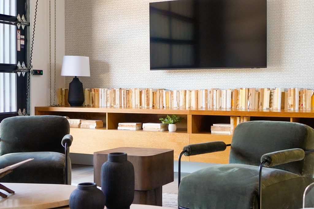 A living room with a flat screen TV mounted on the wall above a wooden shelf.