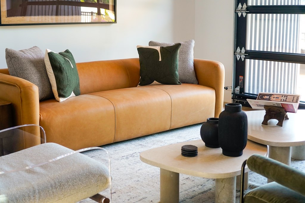 A living room with a tan couch, a white table, and a glass table.