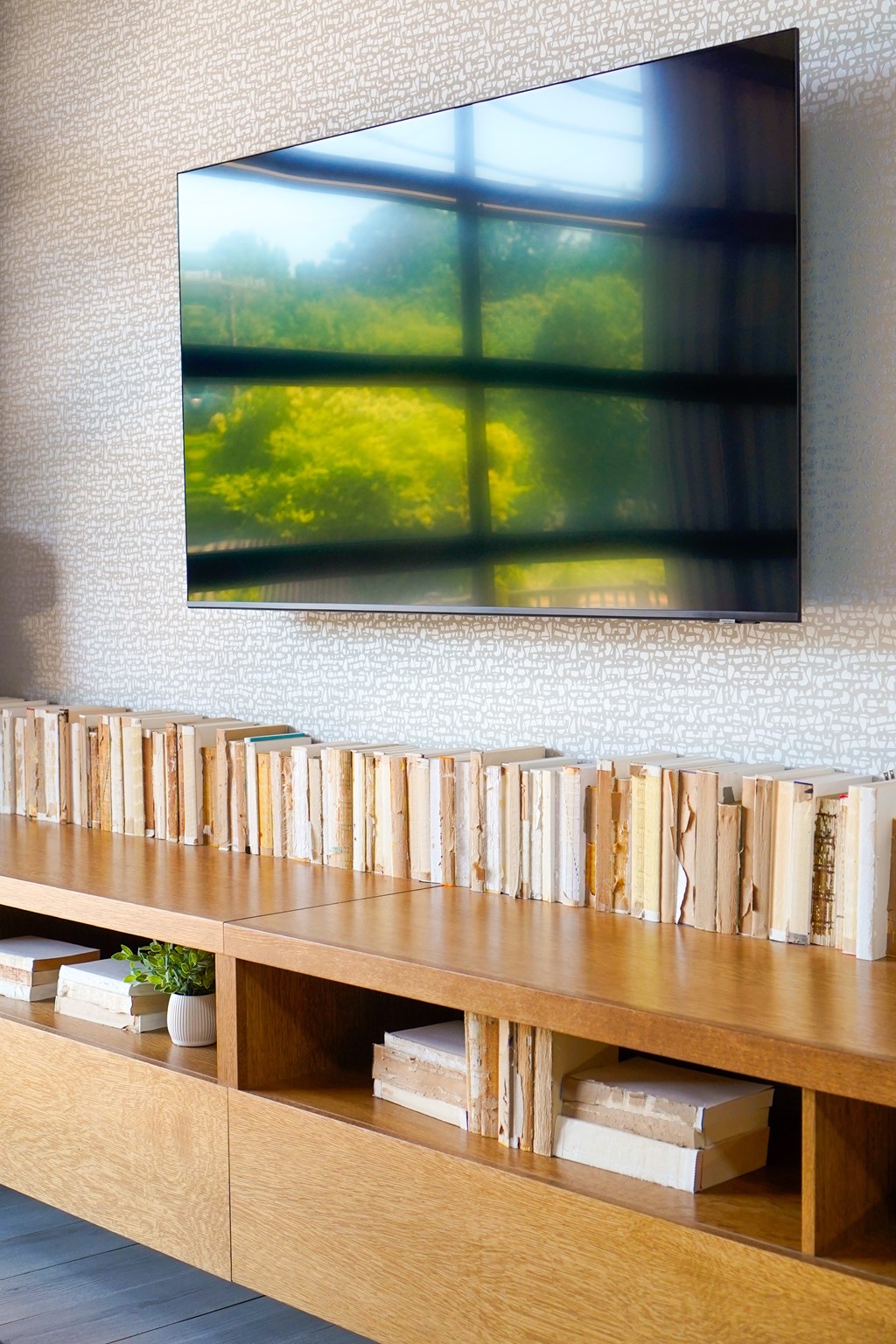 A wall with a picture and a shelf with books and a plant.
