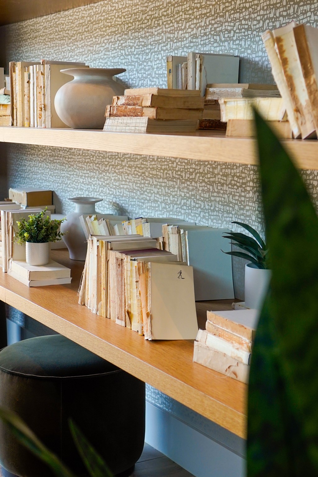 A shelf with books, a vase, and a plant.