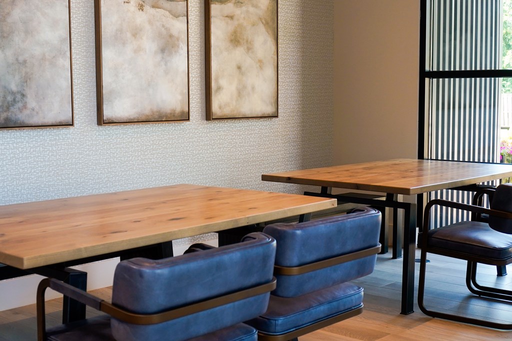 A room with a table and chairs and three pictures on the wall.