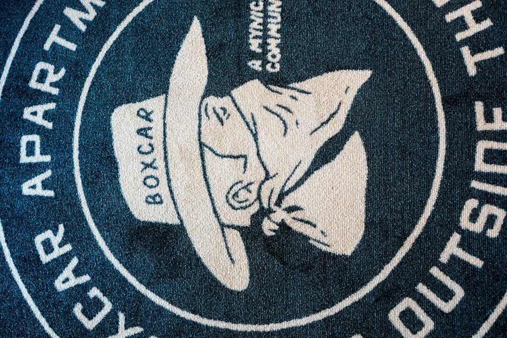 A rug with a cowboy hat and the words "Boxcar" and "Boy Scout Apartments" on it.