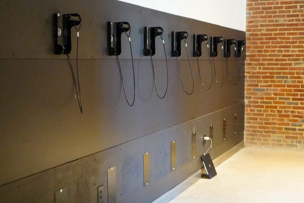 A wall of black hand dryers on a wall.