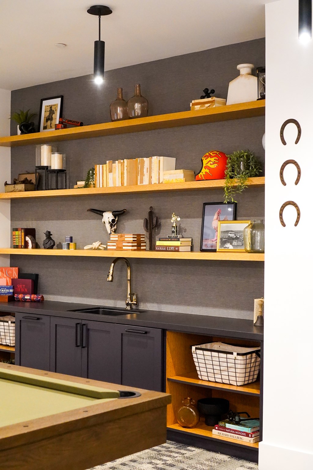 A kitchen with a pool table and shelves with various items.