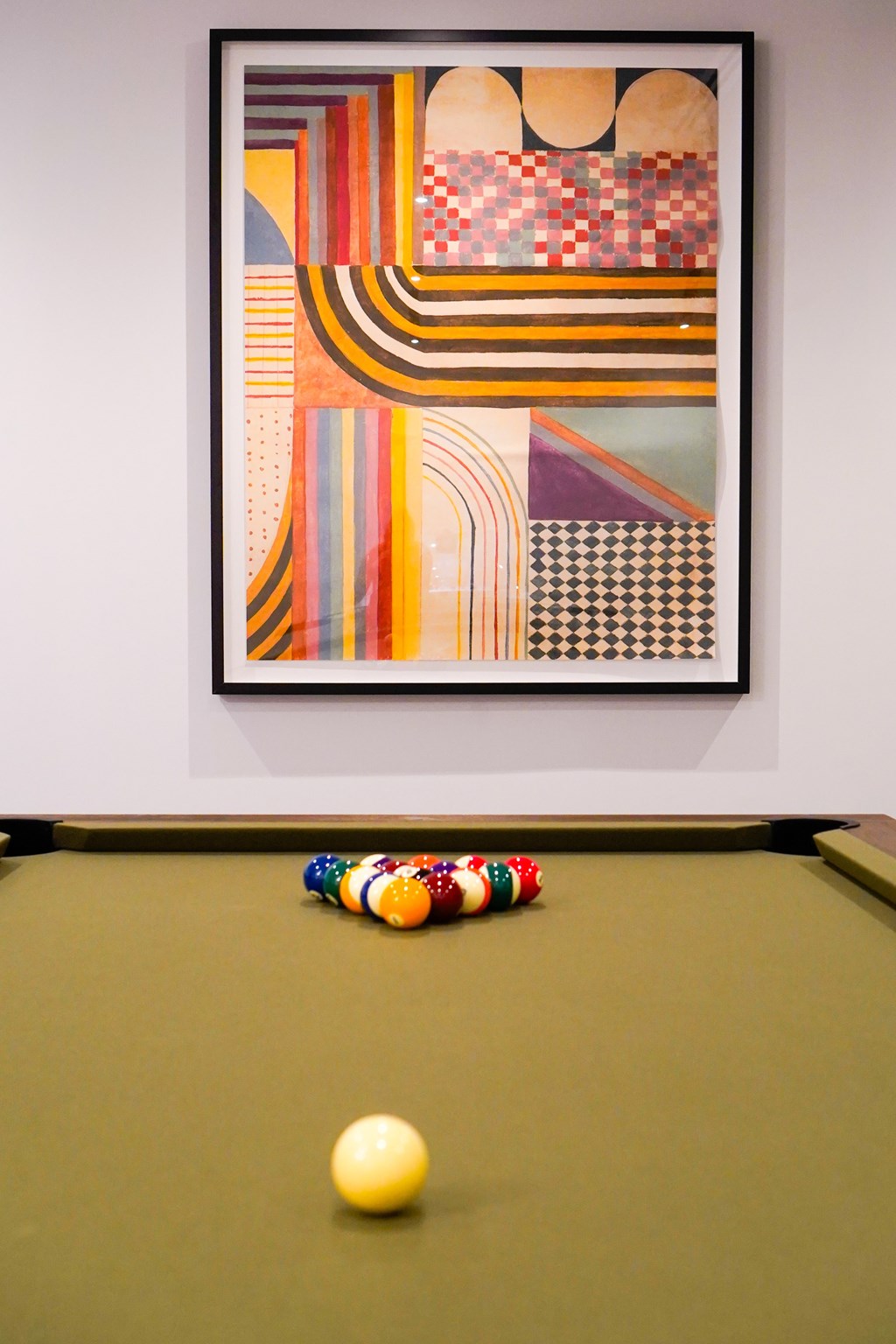 A pool table with a green cloth and a yellow ball in the middle.
