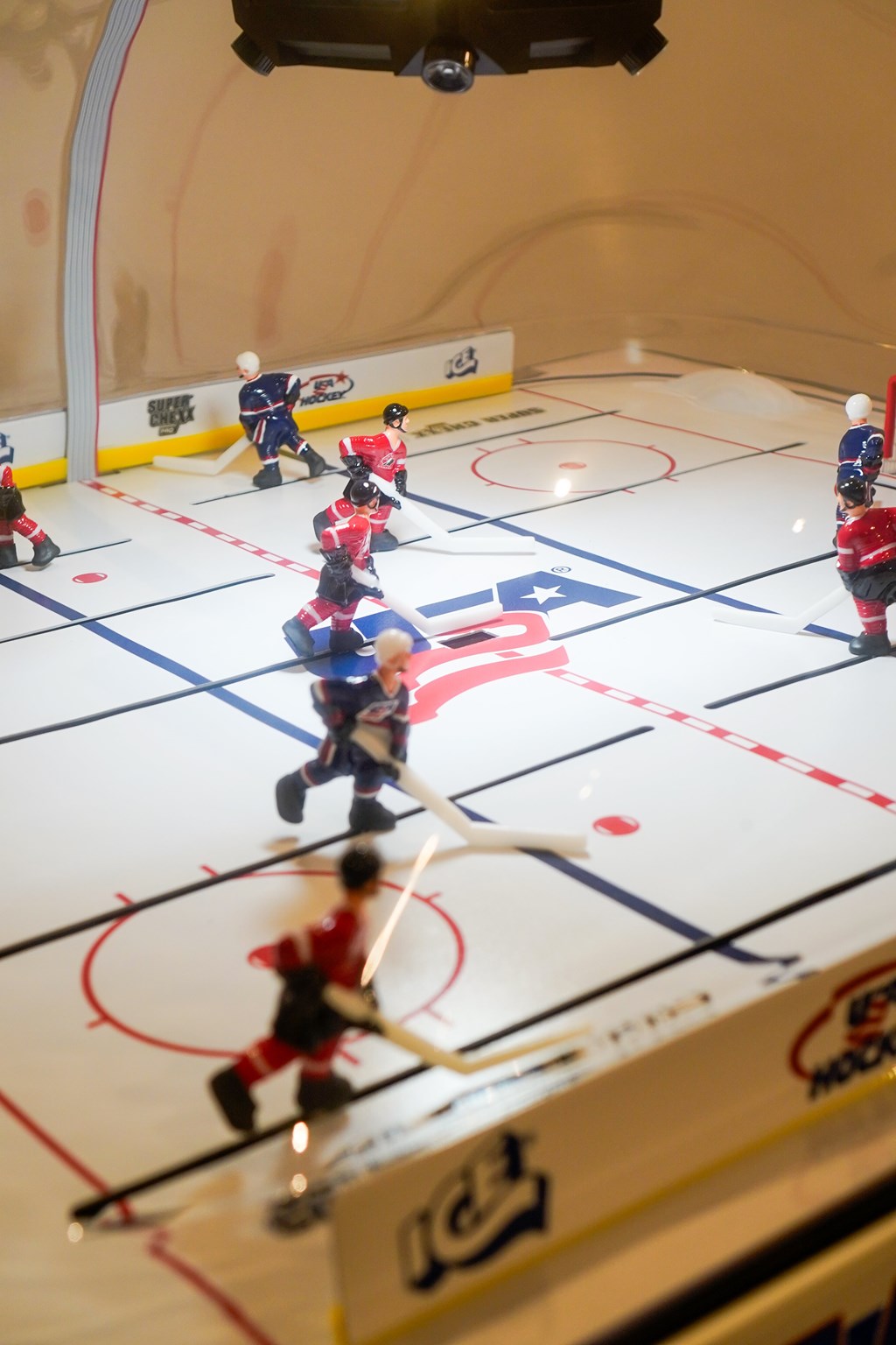 A group of small toy hockey players on a miniature rink.