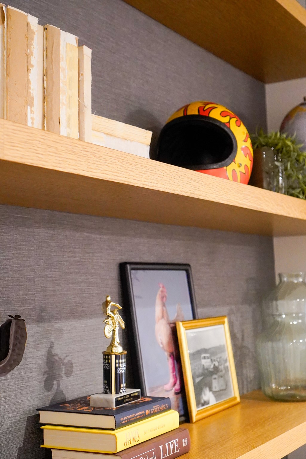 A shelf with a book, a picture frame, a vase, and a trophy.