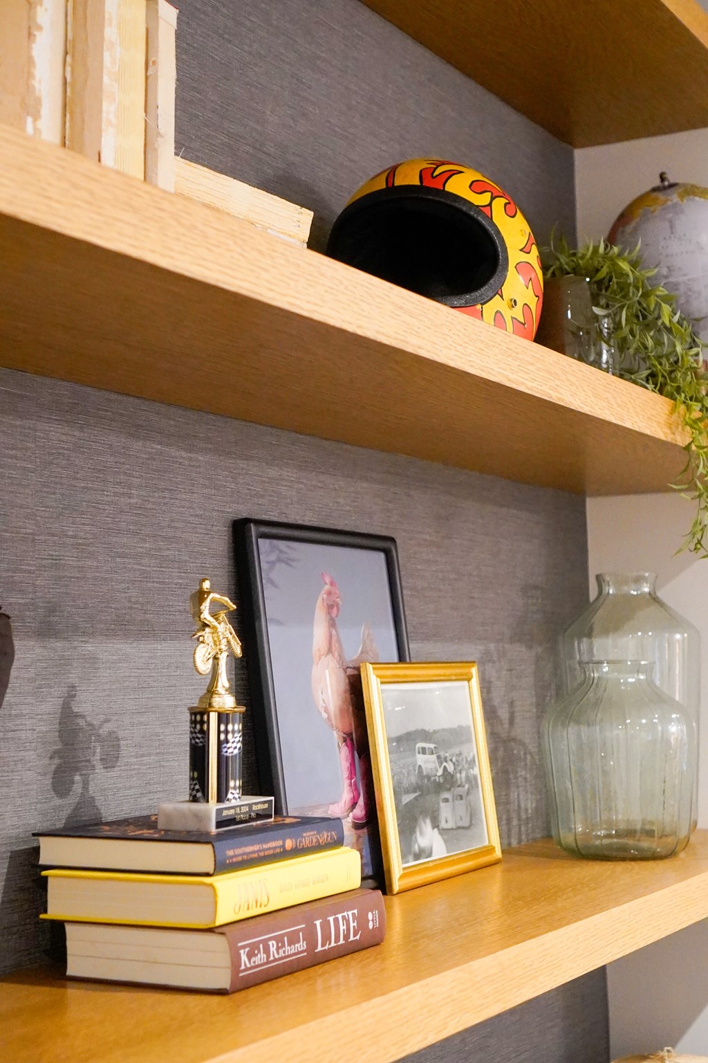 A shelf with a book, a picture frame, a vase, and a trophy.