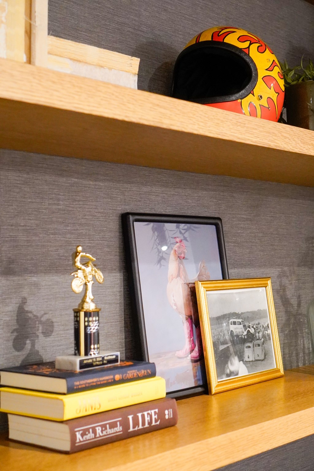 A shelf with a trophy, a picture frame, and a stack of books.