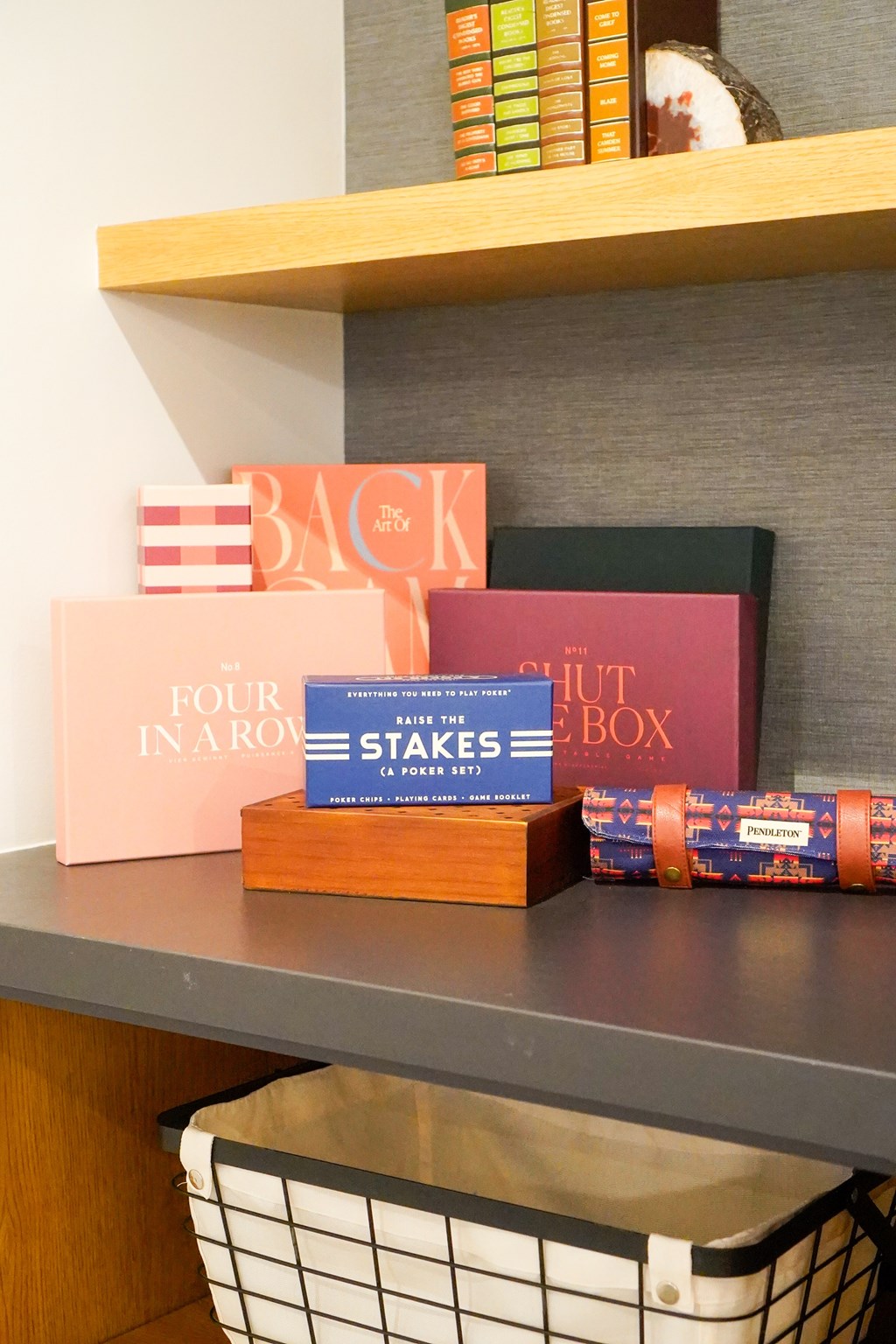 A shelf with a variety of books and a basket underneath.