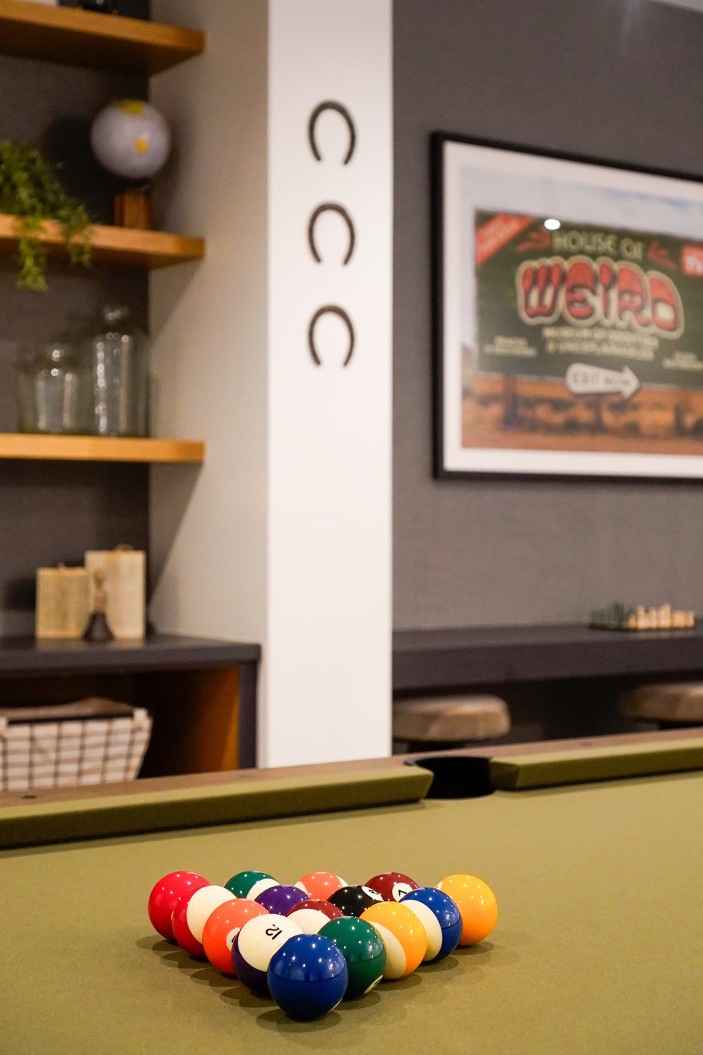 A pool table with a green cloth and a set of balls in the foreground.
