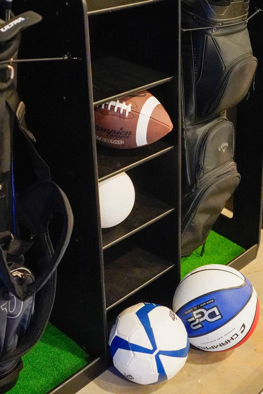 A black shelf with a football, a pair of boots, and two balls.