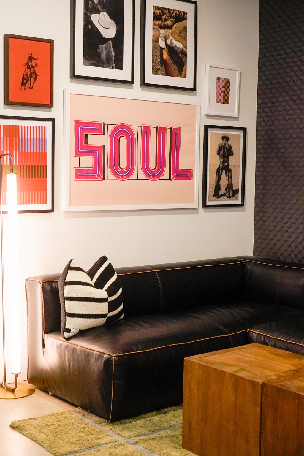 A living room with a black couch and a pink neon sign that says "SOUL".