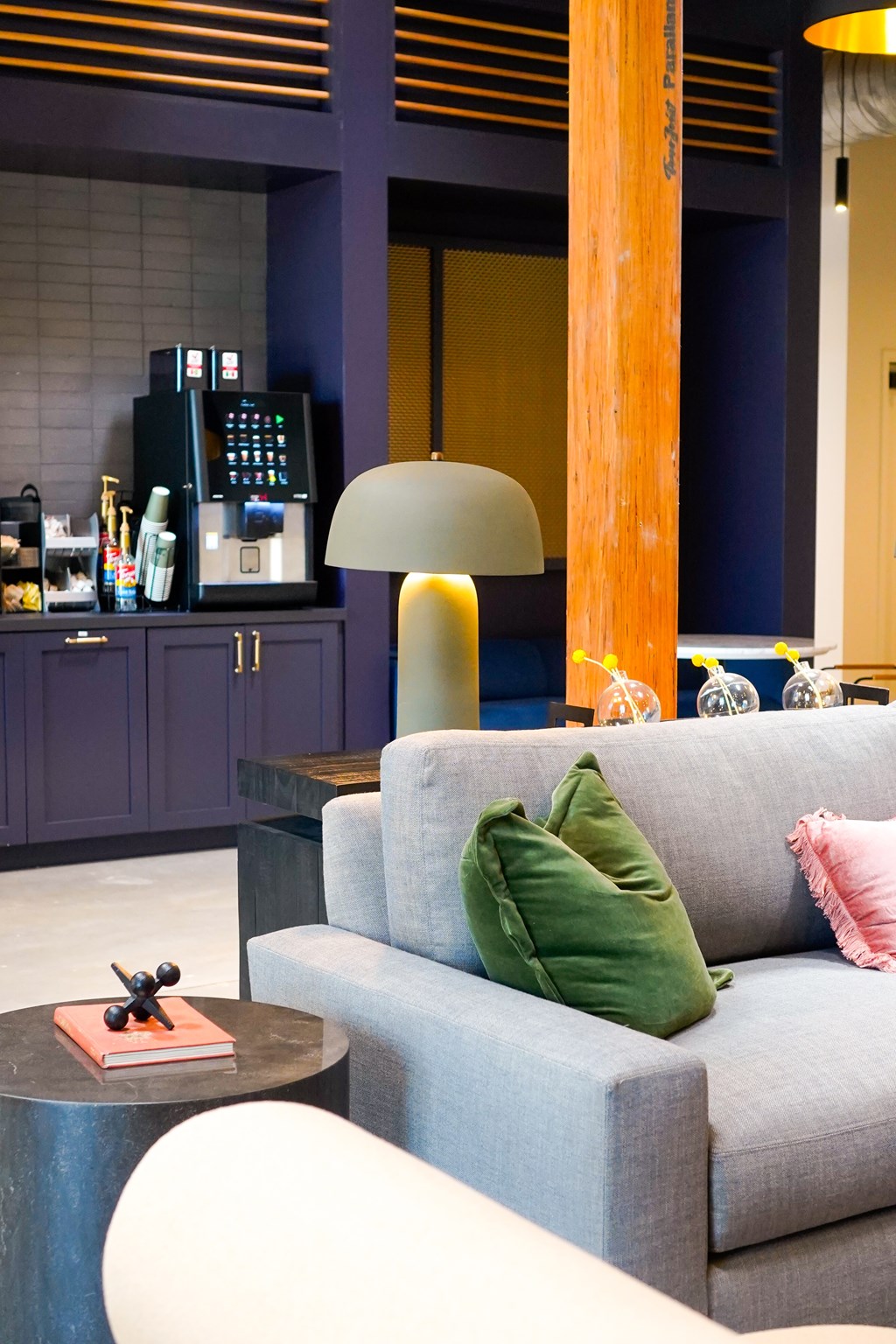 A grey couch with a green pillow sits in front of a tall orange pole.