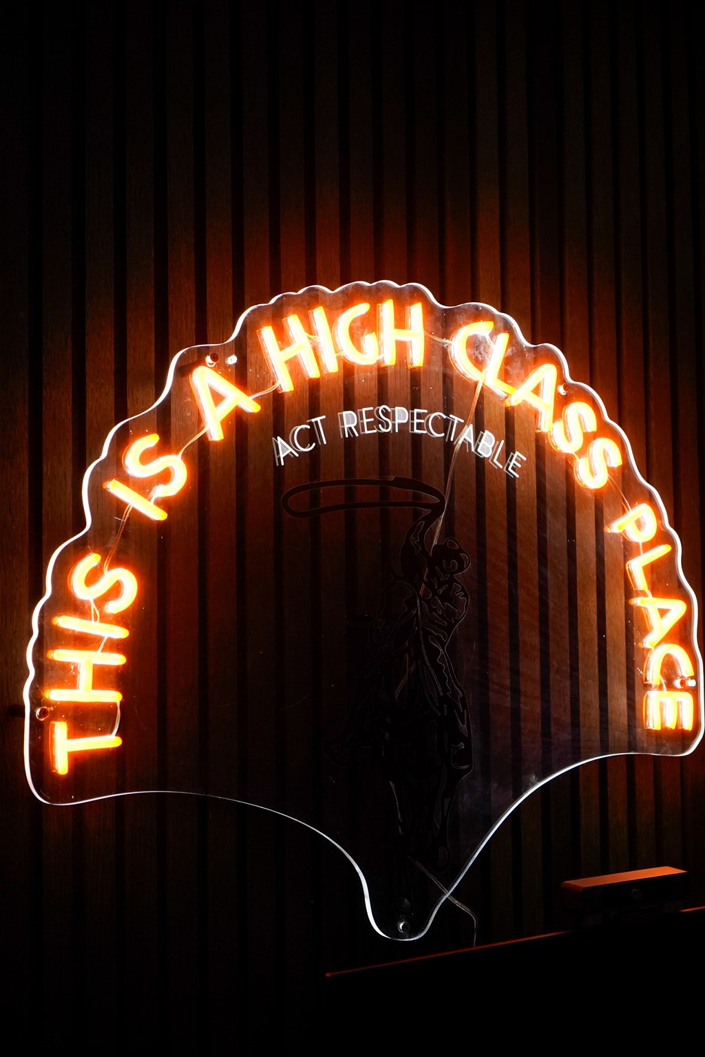 A neon sign that says "This is a high class place" is lit up.
