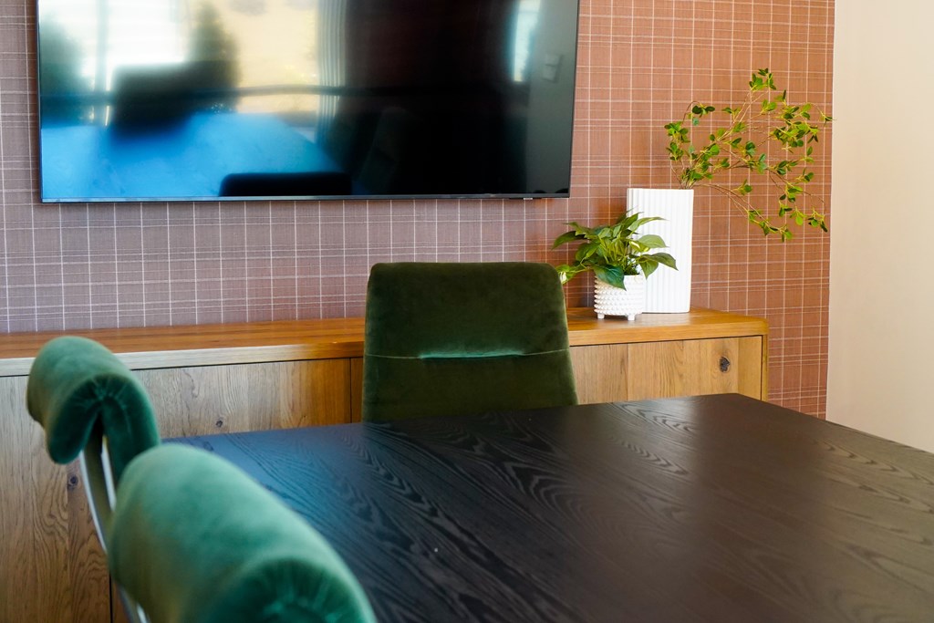 A black table with a green chair in front of a television.